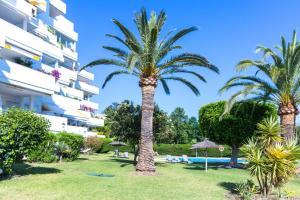 palma w parku obok budynku w obiekcie Lujoso y moderno piso con piscina cerca del campo de golf en Guadalmina Alta Marbella - Quetzal 54 w Marbelli