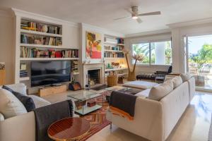 salon z białymi meblami i telewizorem w obiekcie Lujoso y moderno piso con piscina cerca del campo de golf en Guadalmina Alta Marbella - Quetzal 54 w Marbelli