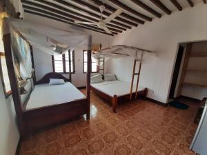 a bedroom with two beds and a ceiling at Ames Nungwi in Nungwi