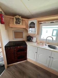 a small kitchen with a stove and a sink at Goldensands in Foryd