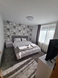 a bedroom with a bed and a desk with a television at Apartament Ultra Central 3 in Hunedoara