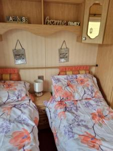 1 dormitorio con 2 camas y mesa con espejo en Goldensands en Foryd