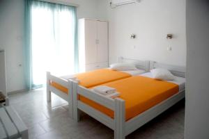 a bedroom with a bed with orange sheets and a window at Ios Penelope in Ios Chora