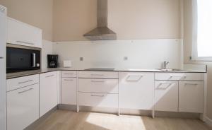 a white kitchen with a sink and a microwave at RuralSuite Hotel Apartamentos in Cascante