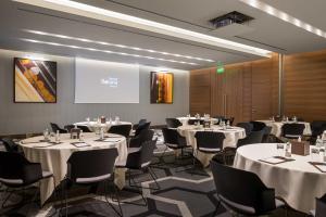 a conference room with tables and chairs and a screen at Slemani Rotana in As Sulaymānīyah