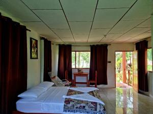 Schlafzimmer mit einem Bett, einem Tisch und Fenstern in der Unterkunft Milía Amazon Lodge in Iquitos