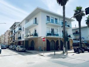 een groot wit gebouw met auto's ervoor geparkeerd bij Eliton in Alghero