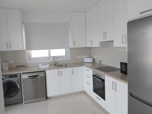 a white kitchen with a sink and a dishwasher at Dinglis Residences 31 in Larnaca