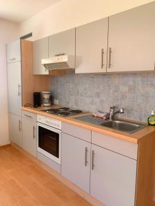 a kitchen with white cabinets and a sink at Garni Rika in Parcines