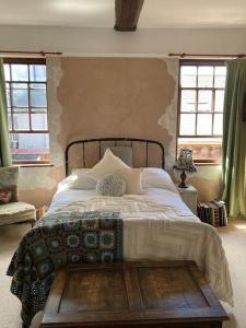 a bedroom with a large bed and two windows at Charming Cottage, Central Taunton. in Taunton