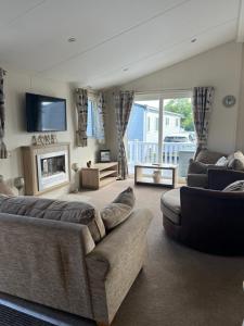 a living room with a couch and a fireplace at Lodge Caravan on Holiday Park in Chichester