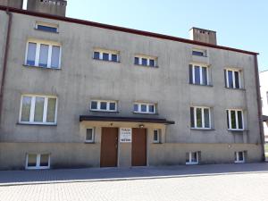 a large concrete building with a brown door at Pokoje u Ludwika in Włodawa