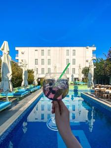 a person holding a drink in front of a pool at Oneiro Resort in Mamaia Sat/Năvodari
