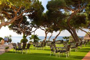 a row of chairs and tables on the grass near the ocean at htop Caleta Palace - Bliss in Platja d'Aro