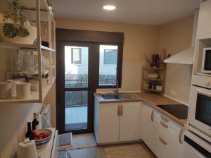 a kitchen with white cabinets and a sink and a window at La Casa OM in Almorox