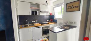 a small kitchen with white cabinets and a sink at MADININA DAY in Saint-Médard-en-Jalles