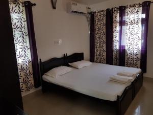 1 cama en una habitación con cortinas y 1 cama con toallas en ARY Royal Palms - 1 BHK en Benaulim