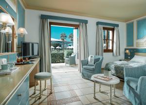 a hotel room with a bed and a living room at Mitsis Royal Mare in Hersonissos