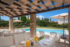 een patio met een tafel en stoelen en een zwembad bij Villa Lara - 11 in Kouklia