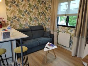 ein Wohnzimmer mit einem Sofa und einem Tisch in der Unterkunft Le Clos des Feugrais - Calme & Confort in Saint-Aubin-lès-Elbeuf