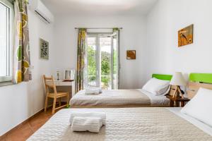 1 dormitorio con 2 camas, escritorio y ventana en ΚΡΗΝΗ, en Skopelos Town