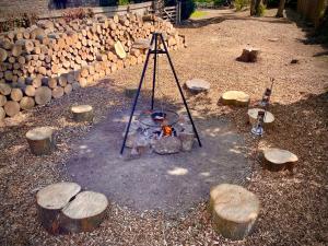 a fire pit with logs and a tripod next to it at Rounceval House in Chipping Sodbury