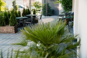 eine Terrasse mit Tischen, Stühlen und Pflanzen in der Unterkunft Vila GRANDE MAMAIA NORD in Mamaia Nord – Năvodari