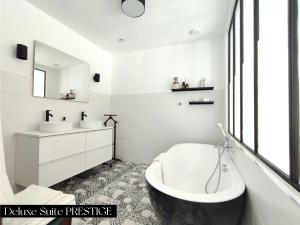 a white bathroom with a tub and a sink and a mirror at Le Prince - Maison d'hôtes in Marseillan
