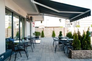 an outdoor patio with tables and chairs and plants at Vila GRANDE MAMAIA NORD in Mamaia Sat/Năvodari