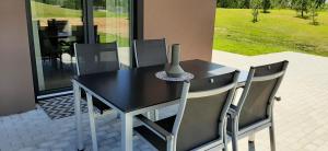 - une table à manger noire avec des chaises et un vase dans l'établissement Vila Galadusis prie ežero, à Lazdijai