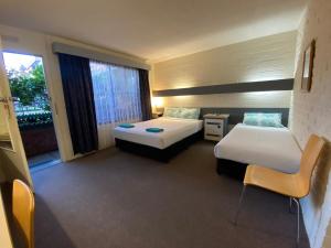 a hotel room with two beds and a window at Mahogany Motel Warrnambool in Warrnambool