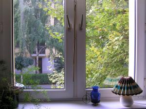 a window with a blue vase and a lamp on a window sill at Belvárosi Studio Apartman in Győr