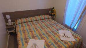a small bedroom with a bed and a table with two towels at Villaggio Santo Stefano in Vieste