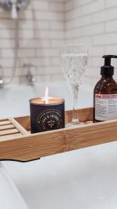 a candle and a wine glass on a wooden tray at Bluebell Copse Cottages New Forest with Hot Tub in Southampton