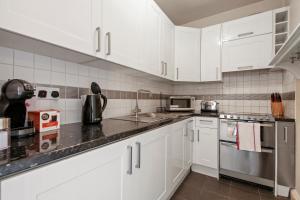 a kitchen with white cabinets and stainless steel appliances at 1 Bed Executive Apartment near Liverpool Street Station FREE WIFI by City Stay Aparts London in London