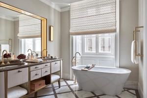 a bathroom with a tub and a sink and a mirror at Rosewood Vienna in Vienna