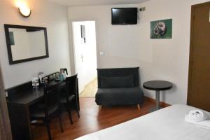 a bedroom with a desk and a chair and a mirror at Hotel Le Coureau in Saint-Trojan-les-Bains