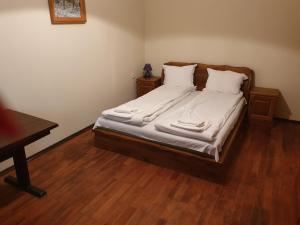een slaapkamer met een bed met witte lakens en houten vloeren bij Guest House Fedor in Ribarica