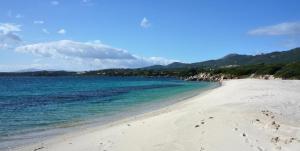 a beach with the ocean and mountains in the background at Hotel Palumbalza Porto Rotondo in Porto Rotondo