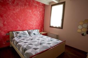 ein Schlafzimmer mit einem Bett mit einer roten Wand in der Unterkunft Residence dei Frutti pieno centro - Il Ribes in Padua