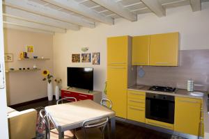 eine Küche mit gelben Schränken, einem Tisch und einem TV in der Unterkunft Residence dei Frutti pieno centro - Il Ribes in Padua