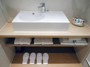 a bathroom with a sink and two pairs of shoes at Mercure Hotel Schiphol Terminal in Schiphol