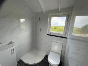 uma casa de banho branca com um WC e uma janela em AC/DC Glamping em New Aberdour