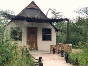 una piccola casa bianca con una porta in legno di Gwango Heritage Resort a Dete