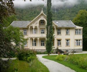 una gran casa blanca con un camino delante de ella en Lindstrøm Hotel, en Lærdalsøyri