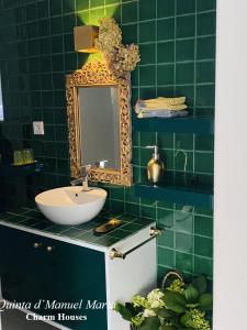 uma casa de banho com azulejos verdes, um lavatório e um espelho. em Quinta D`Manuel Maria- Rural Charm Houses em Amarante