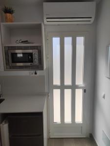 Una puerta a una cocina con microondas y una ventana en LOFT LA CASITA, en Almería