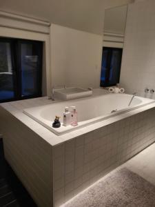 baño con una gran bañera blanca con espejo en Gezellige moderne woning met zwemvijver, en Halle