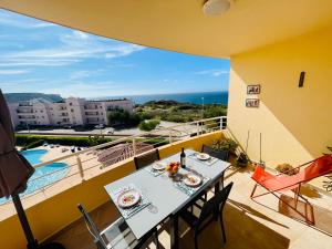 a balcony with a table and a view of the ocean at Vila das Acacias in Luz