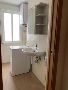 baño blanco con lavabo y ventana en La Encina Azul Rooms, en Ponferrada